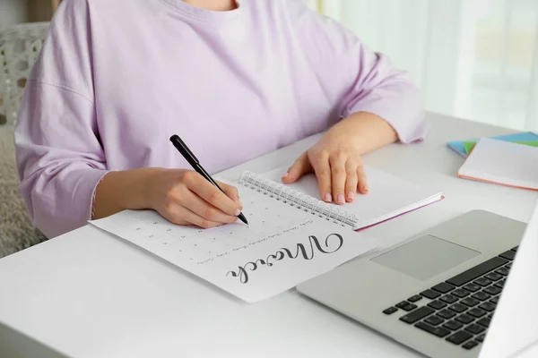 Young woman marking date in calendar at table, closeup — Stock Photo, Image