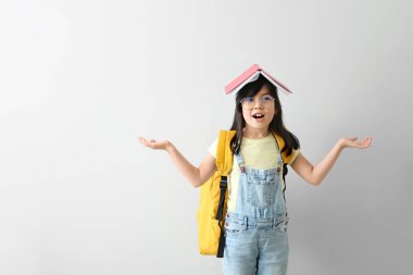 Hafif arka plan üzerinde kitap ile duygusal küçük kız öğrenci portresi