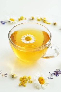 Beyaz arka planda sıcak papatya çayı ve çiçek Fincan