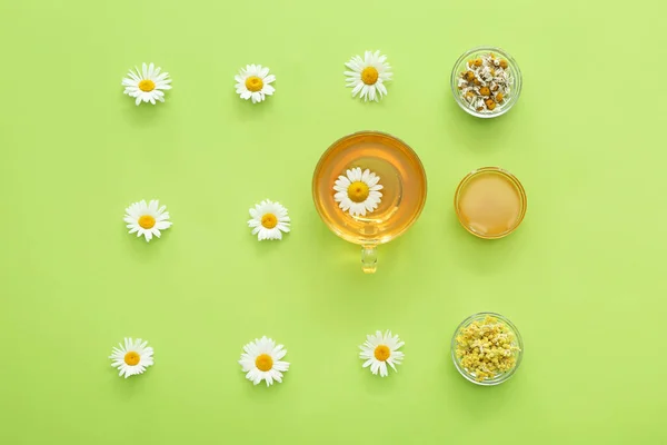 Composición con taza de té de manzanilla caliente y flores sobre fondo de color — Foto de Stock