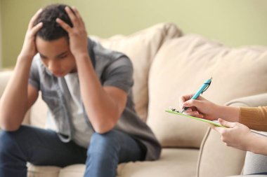 Kadın psikolog ofiste depresif genç erkek ile çalışıyor