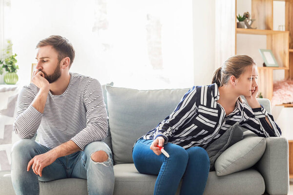 Sad couple with pregnancy test at home