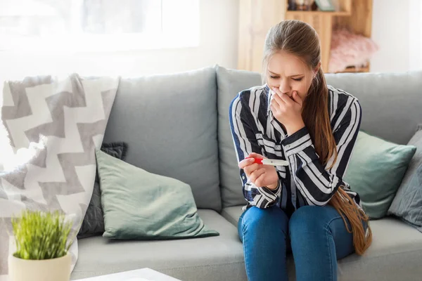 Sad young woman with pregnancy test at home — Stock Photo, Image