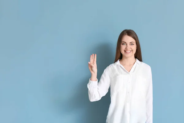 Young deaf mute woman using sign language on color background — Stock Photo, Image