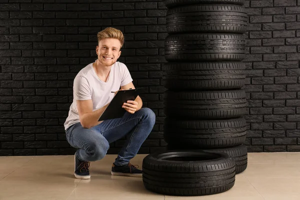 暗い壁に対する車のタイヤを持つ若い男 — ストック写真