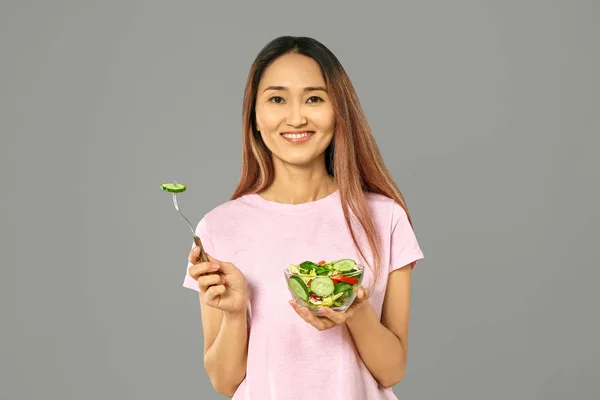 Femme asiatique avec salade de légumes sur fond gris — Photo