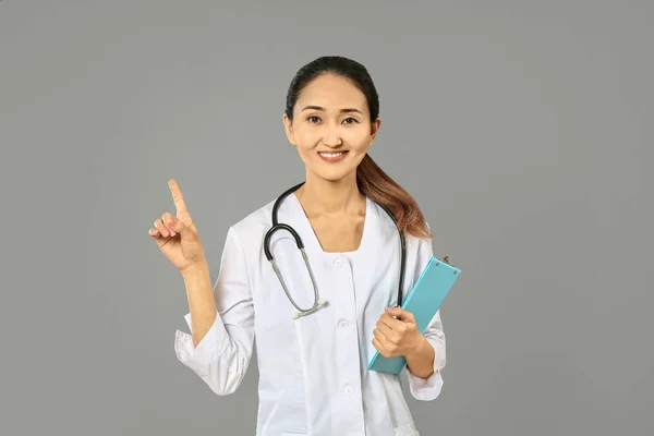 Gri arka planda işaret parmağı nı yükseltmiş Kadın Asyalı doktor — Stok fotoğraf