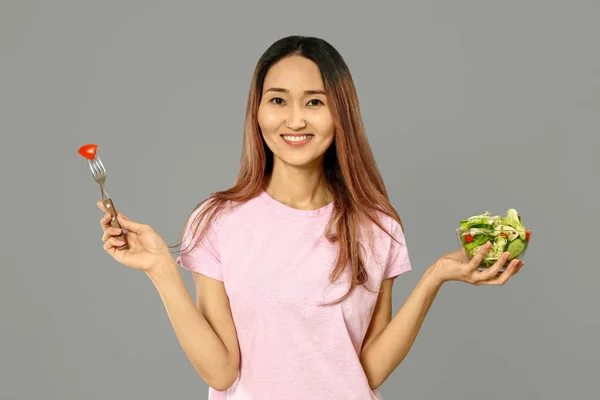 Femme asiatique avec salade de légumes sur fond gris — Photo