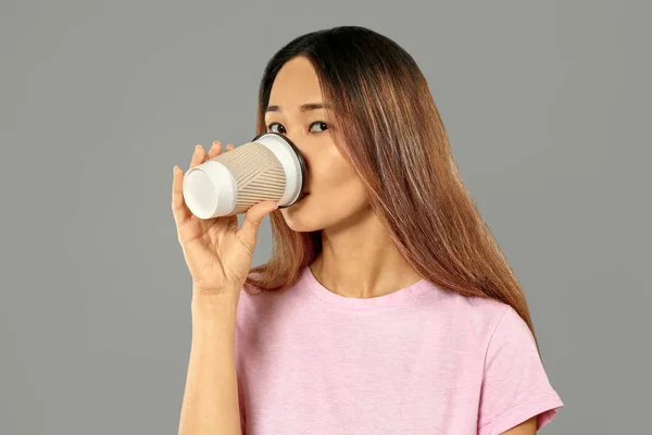 Mujer asiática bebiendo café sobre fondo gris —  Fotos de Stock