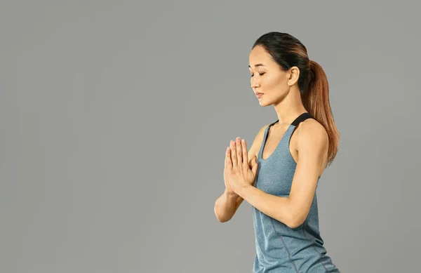 Femme asiatique pratiquant le yoga sur fond gris — Photo