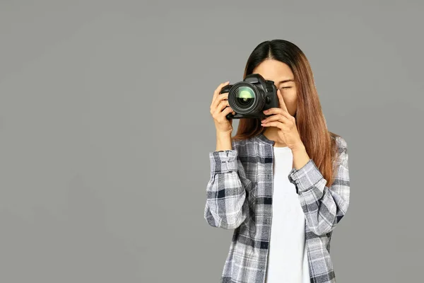 Kobieta azjatycki fotograf na szarym tle — Zdjęcie stockowe