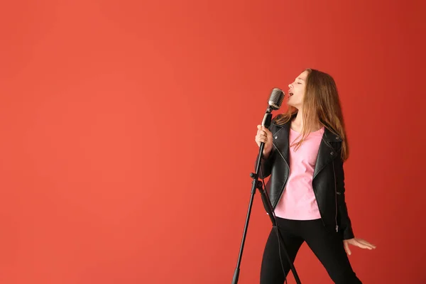 Adolescente com microfone cantando contra fundo de cor — Fotografia de Stock