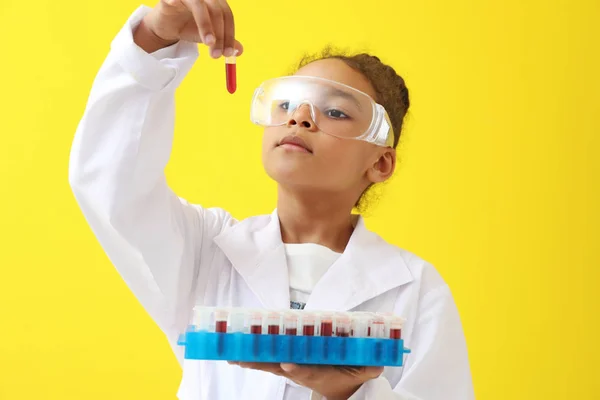 Kis-afro-amerikai laboratóriumi asszisztens gazdaság kémcsövek vérmintákat a színes háttér — Stock Fotó