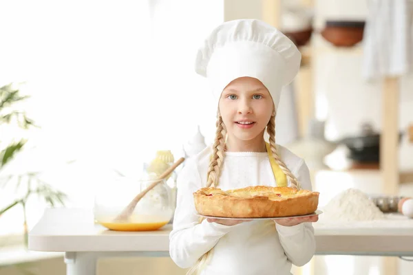 Cute little chef with pie in kitchen — Stock Photo, Image