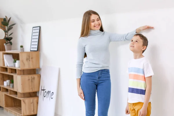 Moeder meten hoogte van haar zoon in de buurt van de muur — Stockfoto