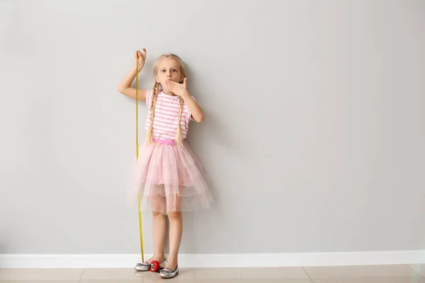 Niedliches kleines Mädchen misst Höhe in der Nähe der Mauer — Stockfoto