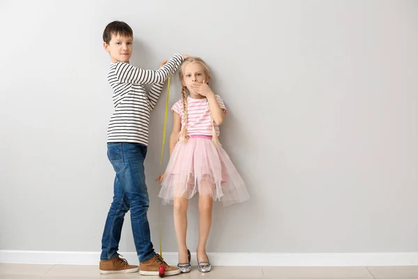 Niedliche kleine Kinder messen Höhe nahe der Mauer — Stockfoto