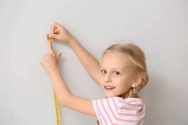 Cute Little Girl wysokość pomiaru w pobliżu ściany — Zdjęcie stockowe