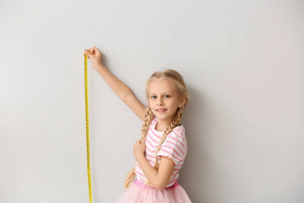 Söt liten flicka som mäter höjd nära väggen — Stockfoto
