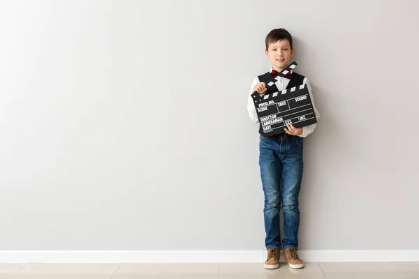 Mały chłopiec z clapperboard w pobliżu białej ścianie — Zdjęcie stockowe