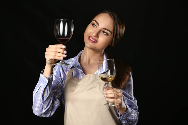 Portrait of elegant female sommelier on dark background