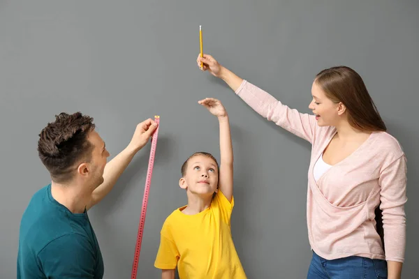 회색 벽 근처에서 아들의 높이를 측정하는 부모 — 스톡 사진