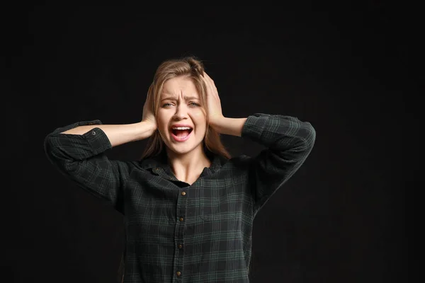 Stressed young woman on dark background