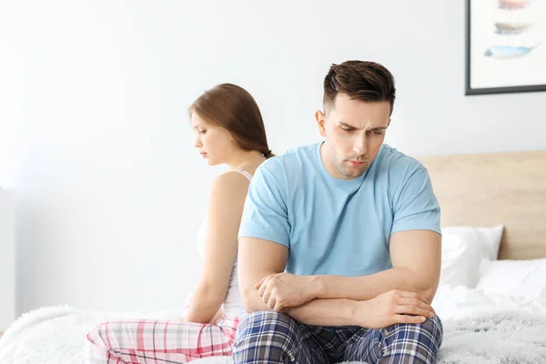 Upset young couple after quarrel sitting on bed — Stock Photo, Image