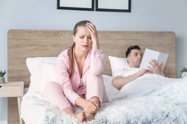Сумна молода жінка після сварки з чоловіком сидить на ліжку — стокове фото