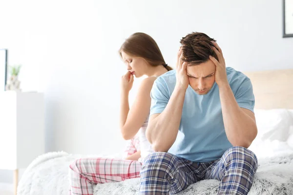 Upset young couple after quarrel sitting on bed — Stock Photo, Image