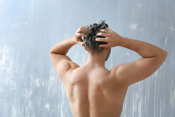 Jóképű férfi mosás haj szürke háttér — Stock Fotó