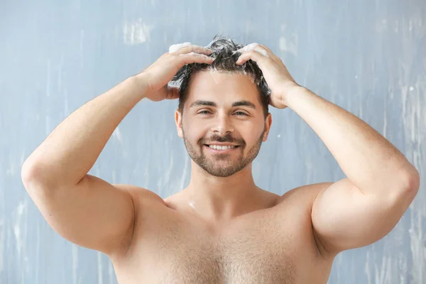 Hombre guapo lavando el cabello sobre fondo gris — Foto de Stock