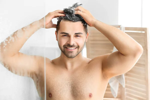 Handsome man washing hair in bathroom