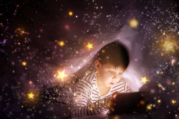 Schattige kleine jongen met tablet pc kijken cartoons onder deken — Stockfoto