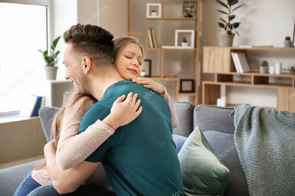 Young couple hugging after quarrel at home