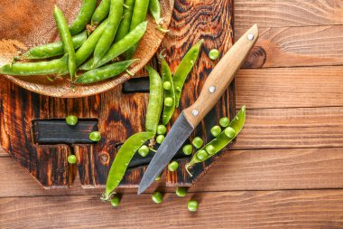 Ahşap masa üzerinde lezzetli taze bezelye ve bıçak ile Kurulu