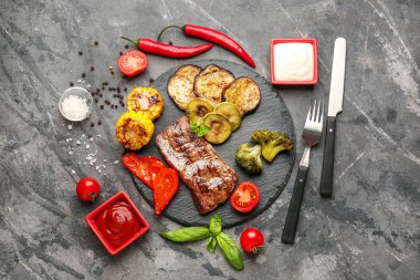 Gri arka planda lezzetli ızgara et ve sebze ile arduvaz tabağı