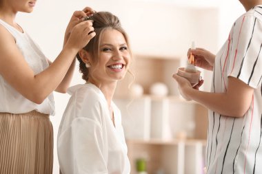 Profesyonel makyaj sanatçısı ve kuaför evde genç gelin ile çalışıyor