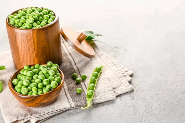 Cuenco y frasco con sabrosos guisantes frescos sobre fondo gris — Foto de Stock