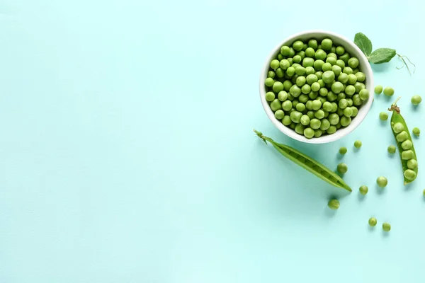 Cuenco con sabrosos guisantes frescos sobre fondo de color — Foto de Stock