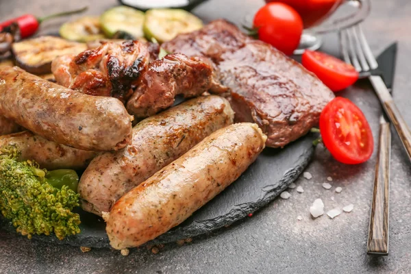 Slate plate with tasty grilled meat with sausages and vegetables on grey background — Stock Photo, Image