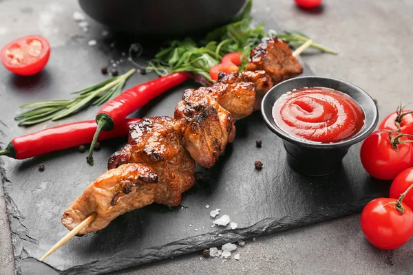 Slate plate with tasty grilled meat and sauce on table