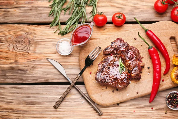Board with tasty grilled meat on wooden table — Stock Photo, Image