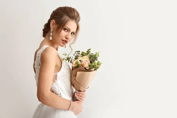 Mooie jonge bruid met boeket bloemen op witte achtergrond — Stockfoto