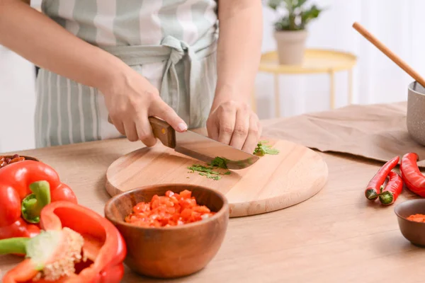 Mujer cortando hierbas frescas en la cocina — Foto de Stock