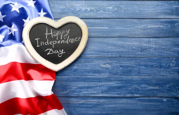 Chalkboard with text HAPPY INDEPENDENCE DAY and national flag of USA on wooden table — Stock Photo, Image