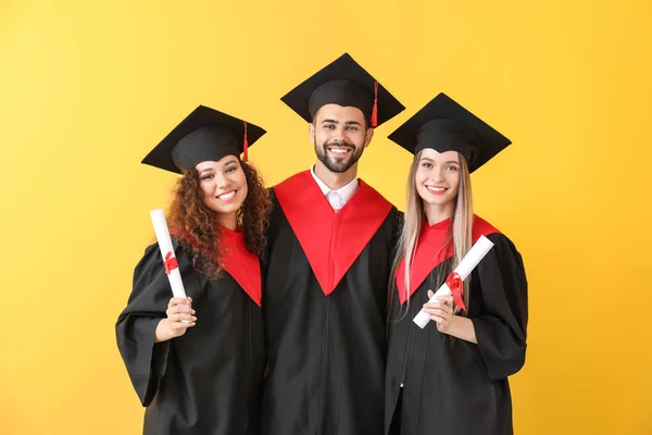 Молодые студенты в бакалаврских халатах на цветном фоне — стоковое фото