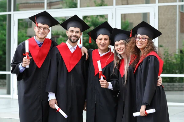 Щасливі студенти в холостяцькому одязі і з дипломами на відкритому повітрі — стокове фото