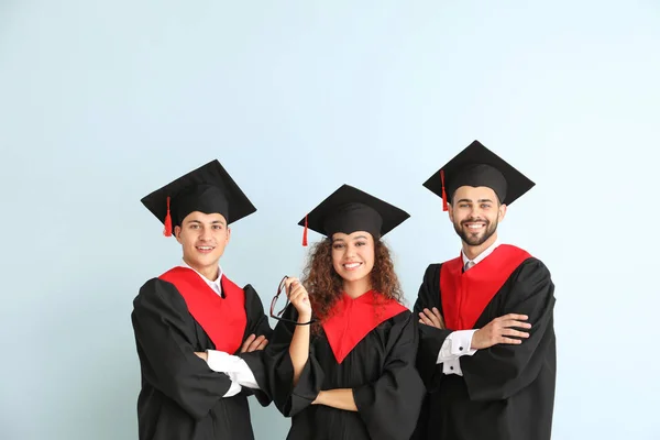 Jóvenes estudiantes en batas de soltero sobre fondo de color — Foto de Stock