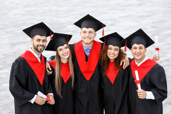 Boldog diákok Bachelor köpenyekben szabadban — Stock Fotó
